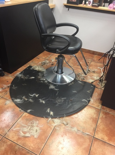 An empty salon chair pictured with Nicole's hair on the floor